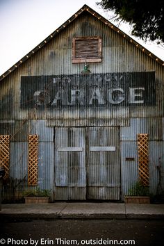 an old building with the word garage painted on it's side and shutters open