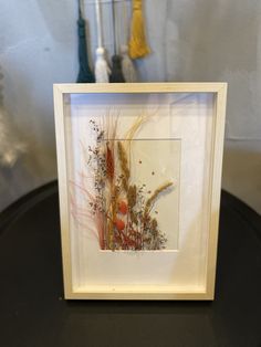 a white frame with some plants in it on top of a black table next to other items