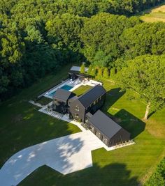 an aerial view of a large house surrounded by trees and green grass with a swimming pool in the middle