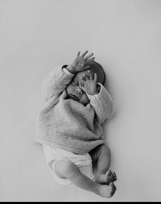 a black and white photo of a baby wrapped in a blanket with his hands up