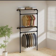 a rack with clothes hanging on it next to a potted plant in a room