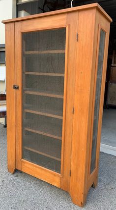 an old wooden bookcase with glass doors on the front and bottom sides, sitting outside