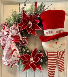 a christmas wreath with a snowman and poinsetti hanging on the front door