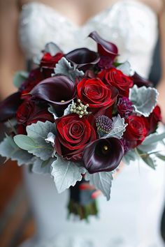 a bride holding a bouquet of red and purple flowers