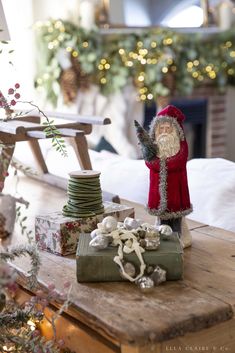 a santa clause figurine sitting on top of a wooden table next to presents