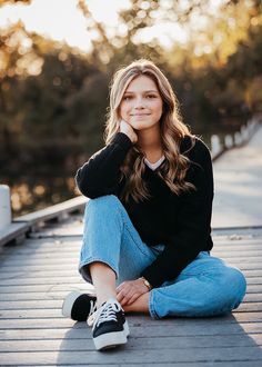 a woman is sitting on the ground with her legs crossed and looking at the camera