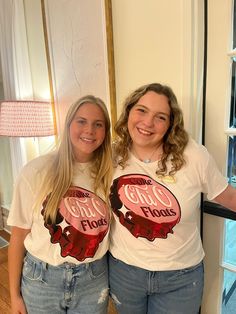 two young women standing next to each other in front of a window wearing t - shirts