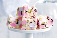 a white plate topped with pieces of cake covered in pink and green frosting on top of a table