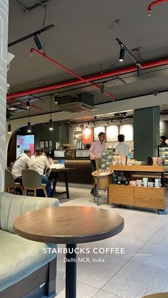 people are sitting at tables in a coffee shop, and one person is standing behind the counter