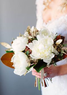 a bride holding a bouquet of white flowers