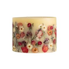 a candle that has flowers on it and is sitting in front of a white background