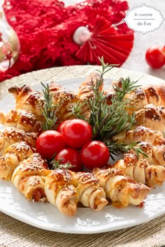 a white plate topped with croissants covered in cherry tomatoes and rosemary sprigs