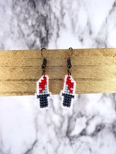 a pair of black and red beaded earrings sitting on top of a piece of wood