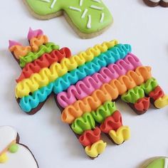 decorated cookies are arranged on a table with cookie cutters in the shape of rainbows