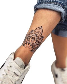 a woman's leg with a tattoo on it and a flower design on the ankle