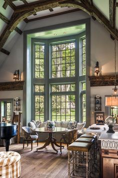 a living room filled with furniture next to a large window covered in lots of windows