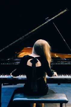 a woman sitting at a piano with her back to the camera