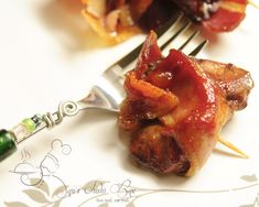 bacon wrapped in toothpicks on a white plate with a green beaded fork