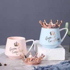 three cups with crowns on them sitting on a table