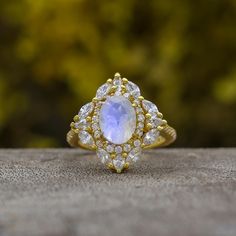 a ring with a rainbow colored stone surrounded by white and yellow diamonds on a wooden surface