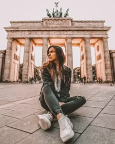 a woman sitting on the ground in front of an arch