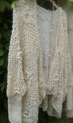 a white crocheted cardigan hanging from a tree