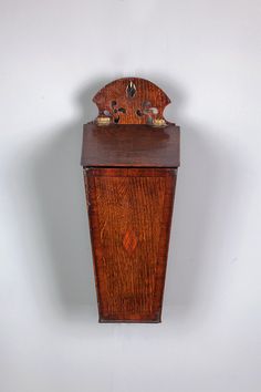 an old wooden clock hanging on the wall in front of a white wall with no one around it