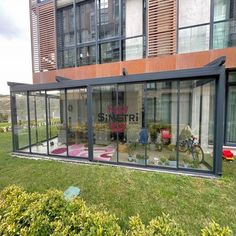 a glass enclosed patio in front of an apartment building with bikes parked on the lawn