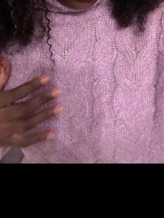 a close up of a person wearing a purple sweater and holding their hands in front of her chest