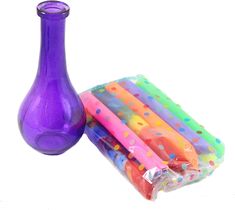 a purple vase sitting next to a pile of plastic straws