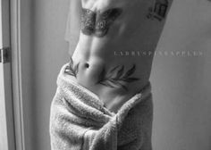 black and white photograph of a man with tattoos on his stomach wrapped in a towel