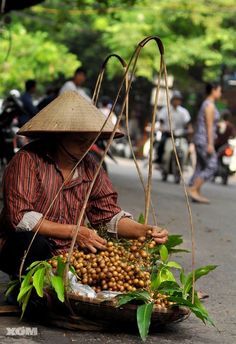 a woman sitting on the ground with lots of food in her hand and wearing a straw hat