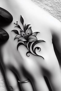 a black and white photo of a woman's hand with a flower tattoo on it