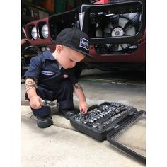 a little boy that is playing with some kind of toolbox in front of a car