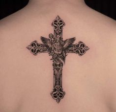 a cross tattoo on the back of a woman's upper body, with an intricate design