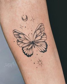 a small butterfly tattoo on the right leg with stars and a crescent moon behind it