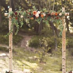 an arch decorated with flowers and greenery in the woods