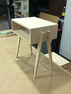 a white table sitting on top of a hard wood floor next to a wooden shelf