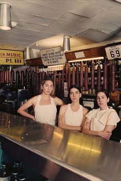 three women in aprons are behind the bar