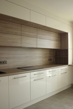 an empty kitchen with wooden cabinets and white cupboards, in the middle of a large open floor plan