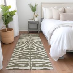 a white bed sitting next to a green plant on top of a hard wood floor