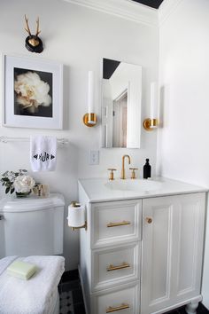 a white bathroom with black and gold accents