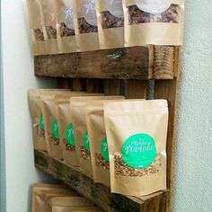 several bags of granola are hanging on a wooden rack in front of a wall