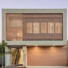 a modern house with wood slats on the front and side walls, along with two garages