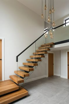 a wooden staircase with glass railing and chandelier