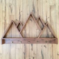 a wooden shelf with three triangle shaped shelves on it's sides, hanging from the wall