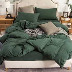 a bed with green comforter and pillows on it