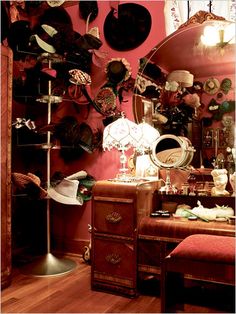 a room filled with lots of hats on top of a wooden table next to a mirror