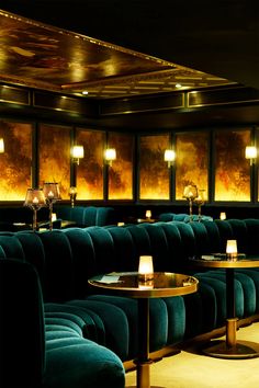 the interior of a fancy restaurant with blue velvet booths and candles lit up on tables