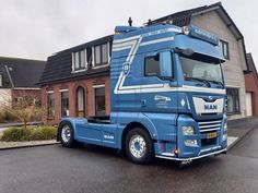 a blue semi truck parked in front of a house